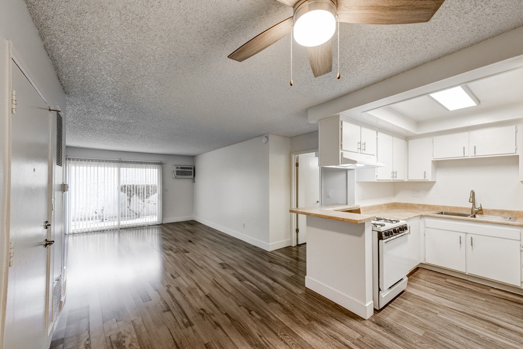 an open kitchen and living room with white cabinets and wood floors