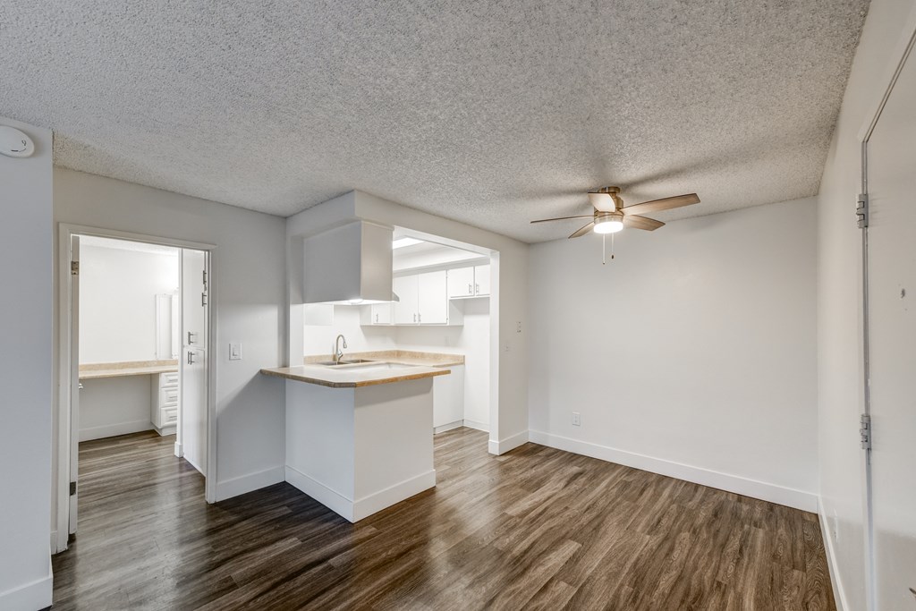 an empty dining room with a kitchen and a ceiling fan