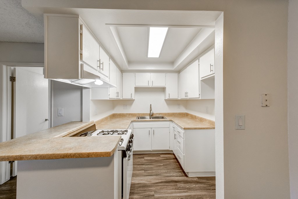 an empty kitchen with white cabinets and a counter top