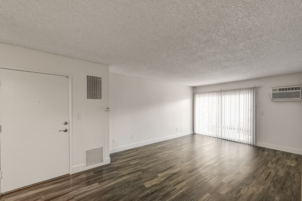 an empty living room with wood flooring and a window