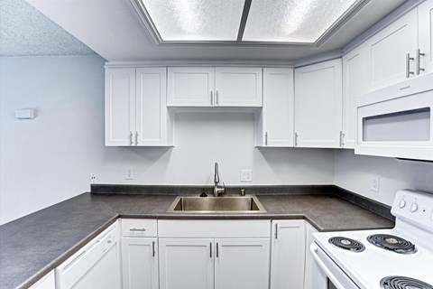 A kitchen with white cabinets and a stove top oven.