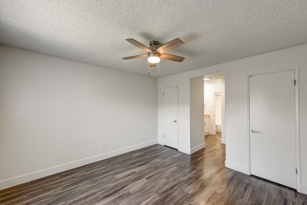 an empty bedroom with a ceiling fan and wood flooring