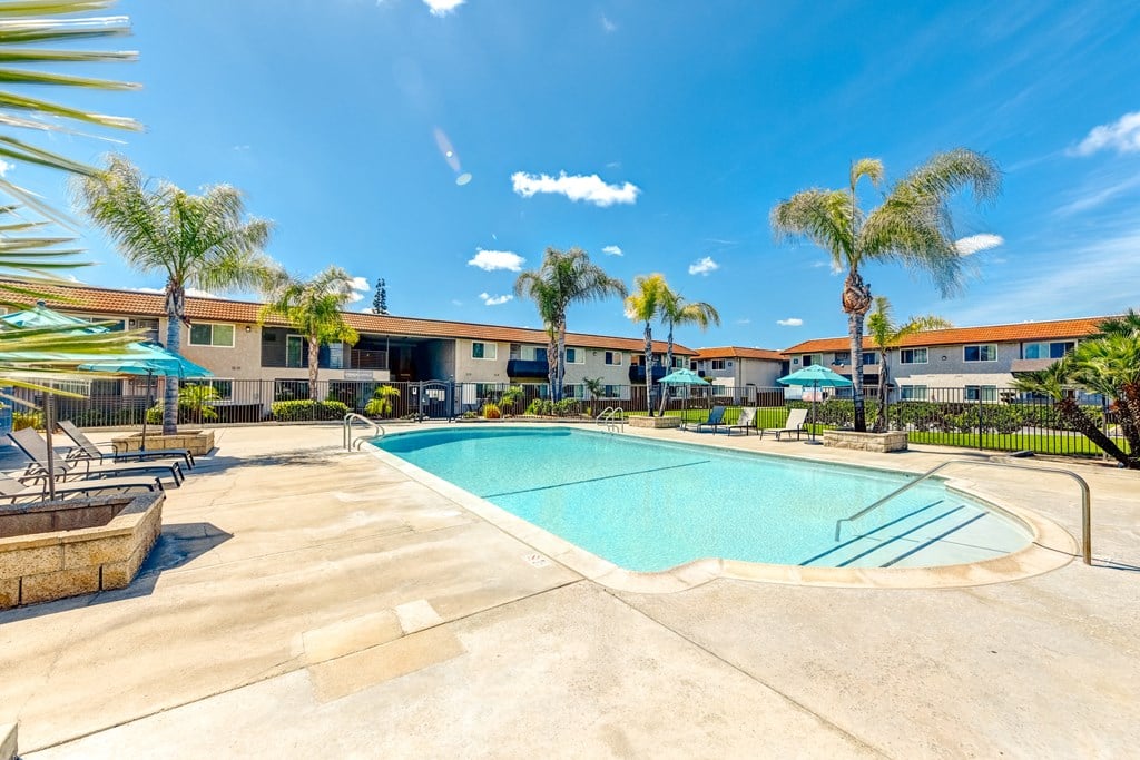 a swimming pool with palm trees and a building in the background
