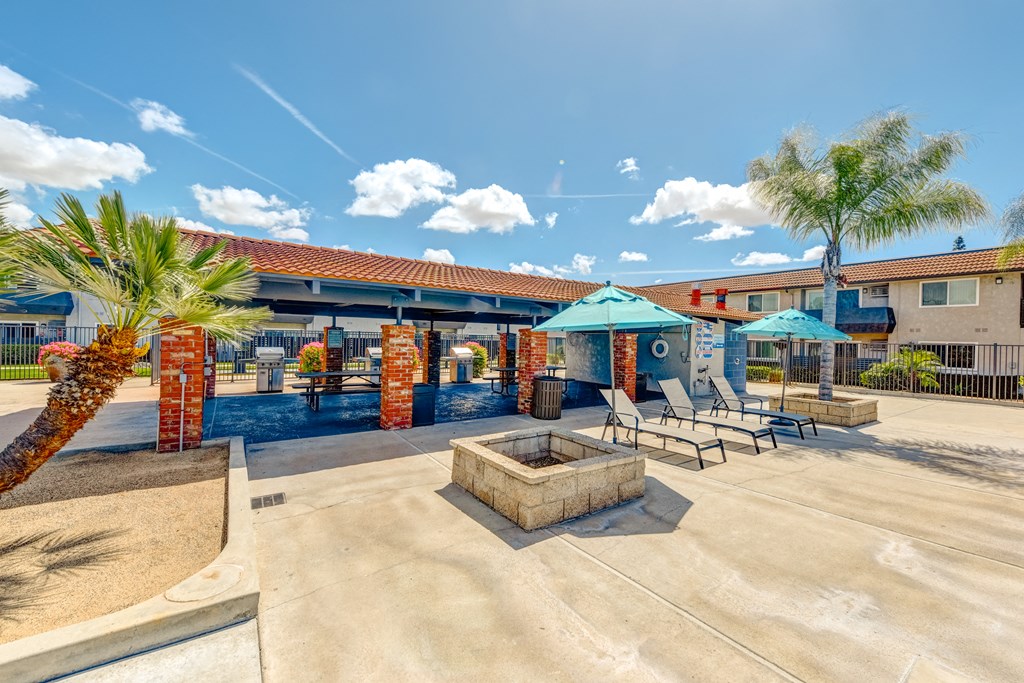 a picnic area with a lounge chairs and umbrellas in front of a building