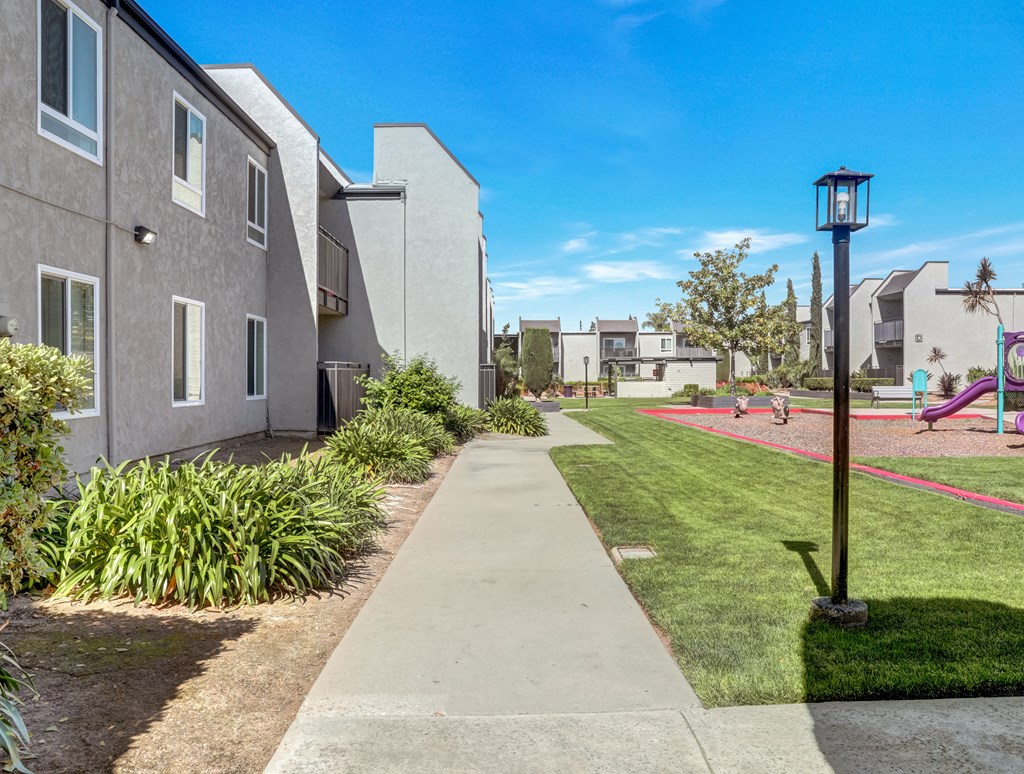 A residential area with a sidewalk and a playground. A residential area with a sidewalk and a playground.