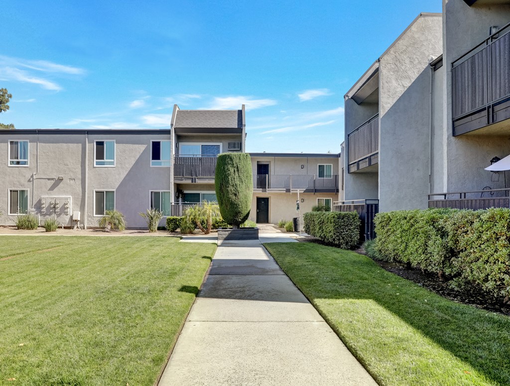A well-maintained lawn leads to a modern apartment building.
