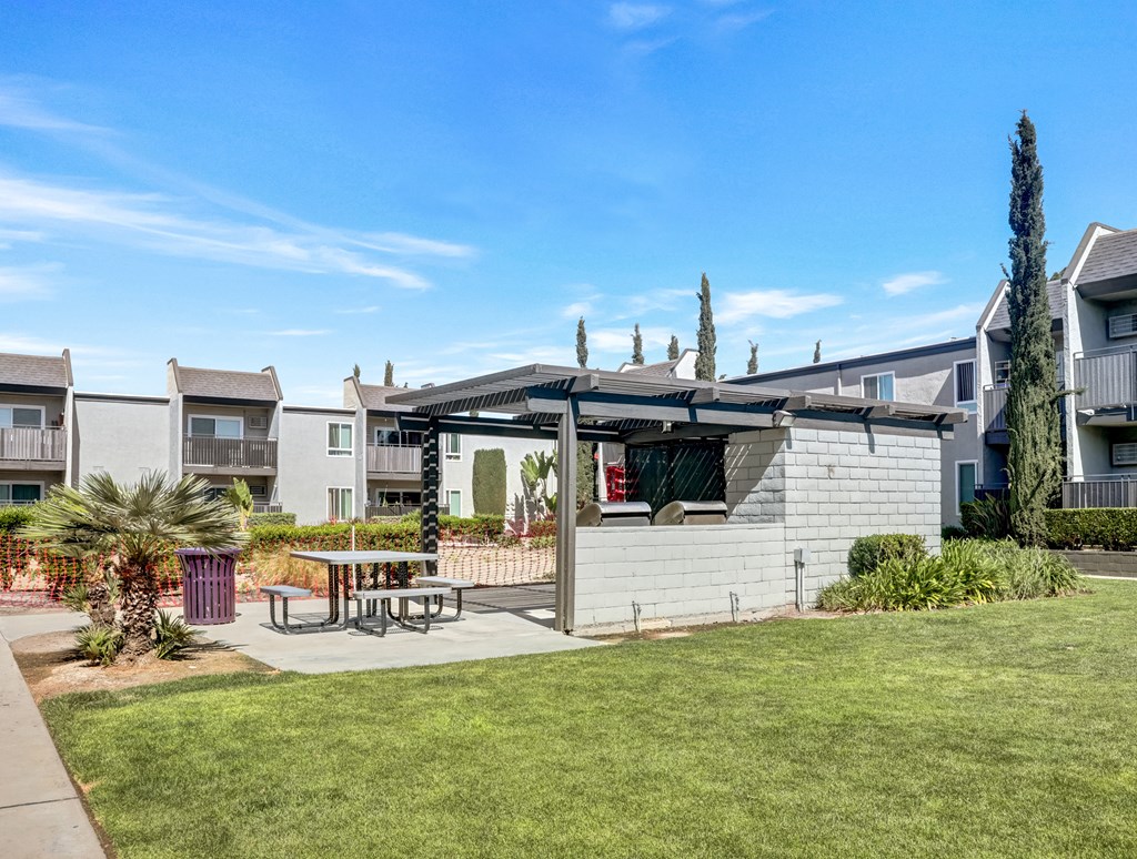 A sunny day at a residential area with apartment buildings and a picnic table.