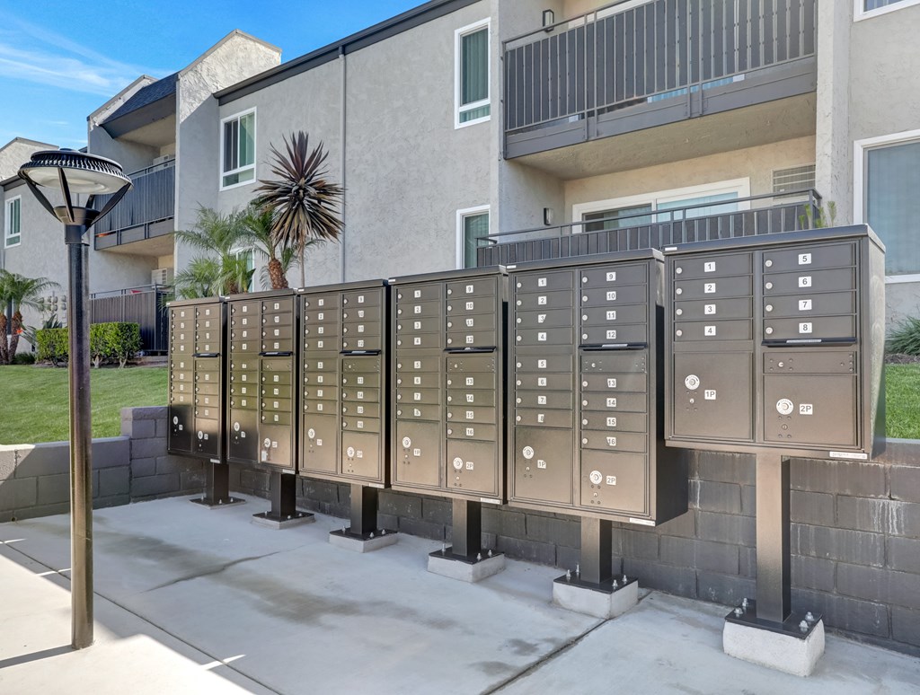 A row of mailboxes are lined up on a sidewalk.