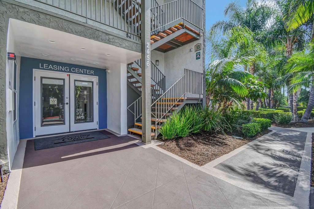 the entrance to a leasing center with stairs and palm trees