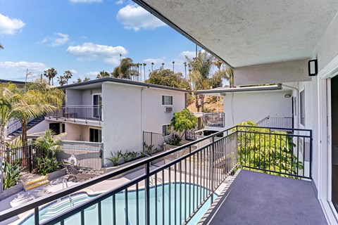 A balcony with a pool and a view of a house and trees.