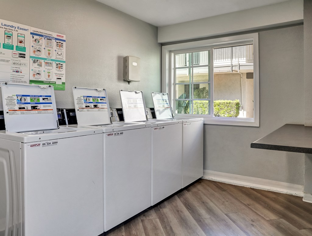 A laundry room with a row of washing machines and a signboard.