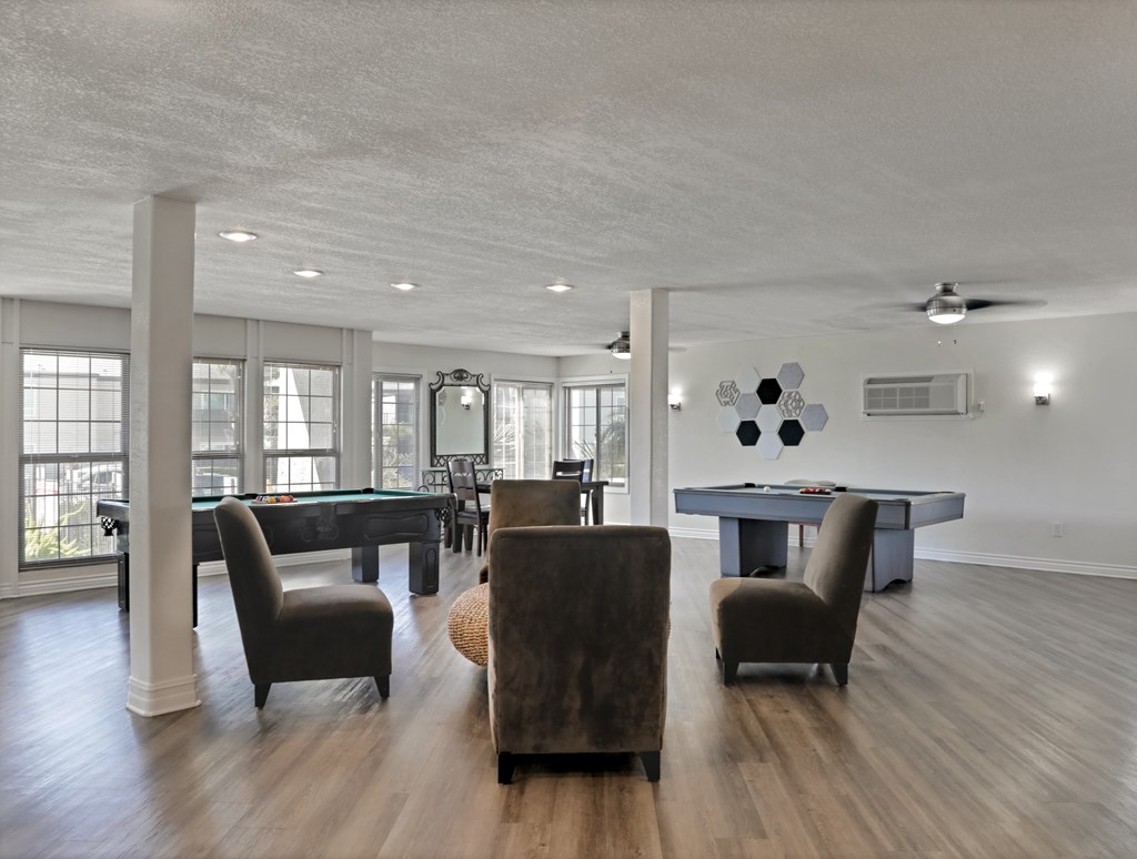 A room with a pool table and chairs.