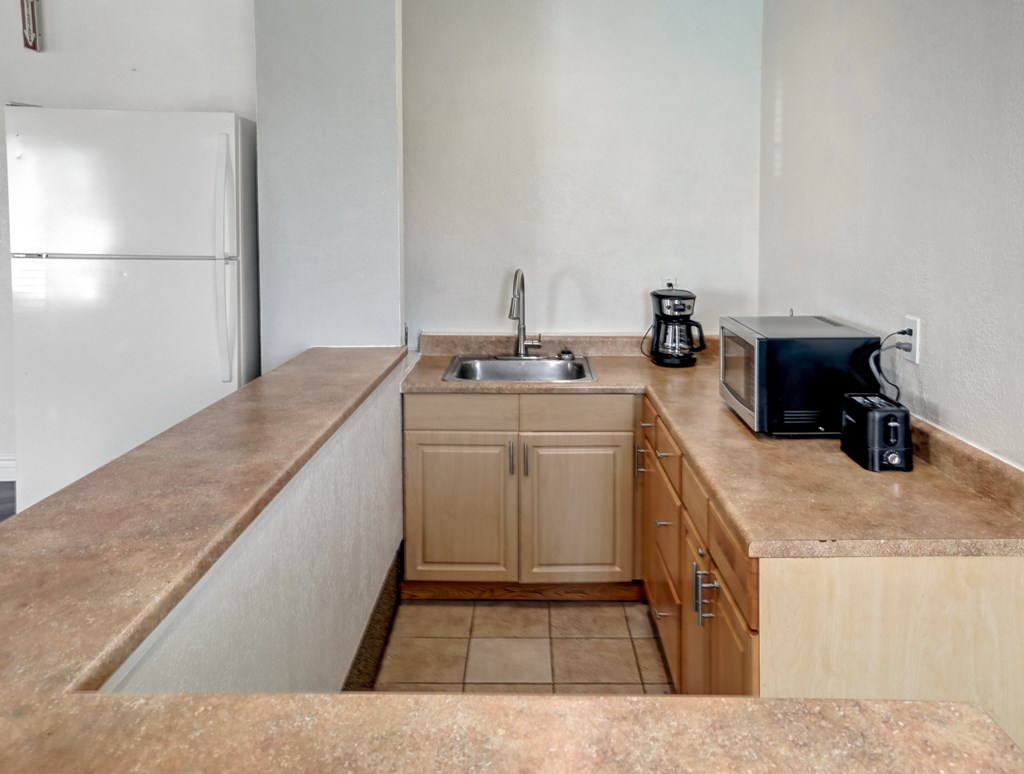 A kitchen with a sink, toaster, and refrigerator.