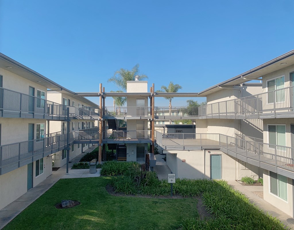 a view of the exterior of an apartment building with stairs and a green lawn