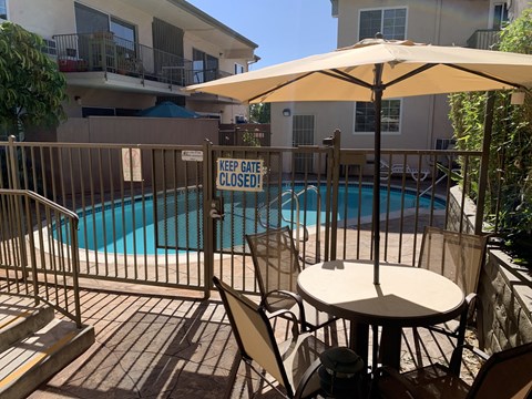 a patio with a table and chairs next to a swimming pool