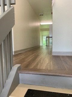 a hallway with a hard wood floor and a staircase