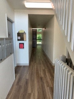 a hallway with a wood floor and a white staircase