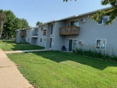 an apartment building with a lawn and a sidewalk