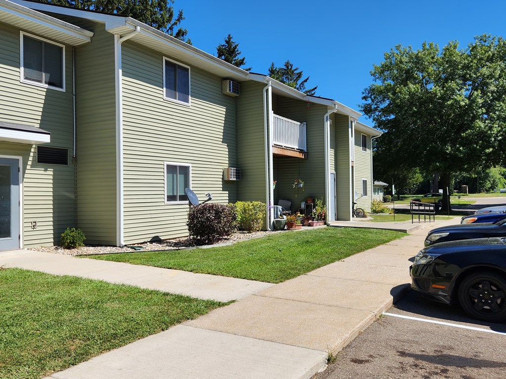 a green two story apartment building with a black car parked in front of it
