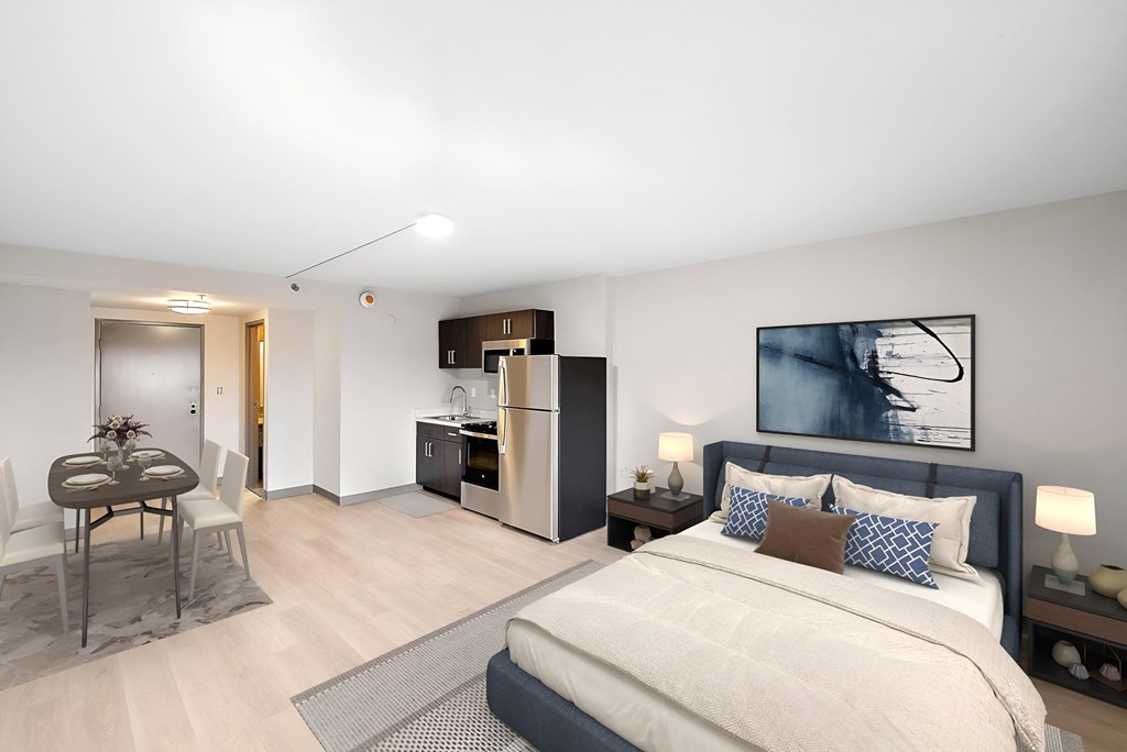 a bedroom with a large bed and a kitchen with a refrigerator