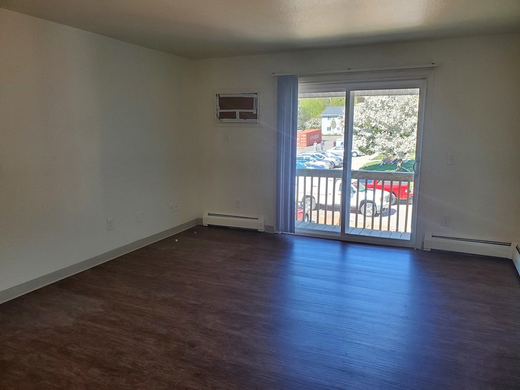 an empty living room with a door to a balcony