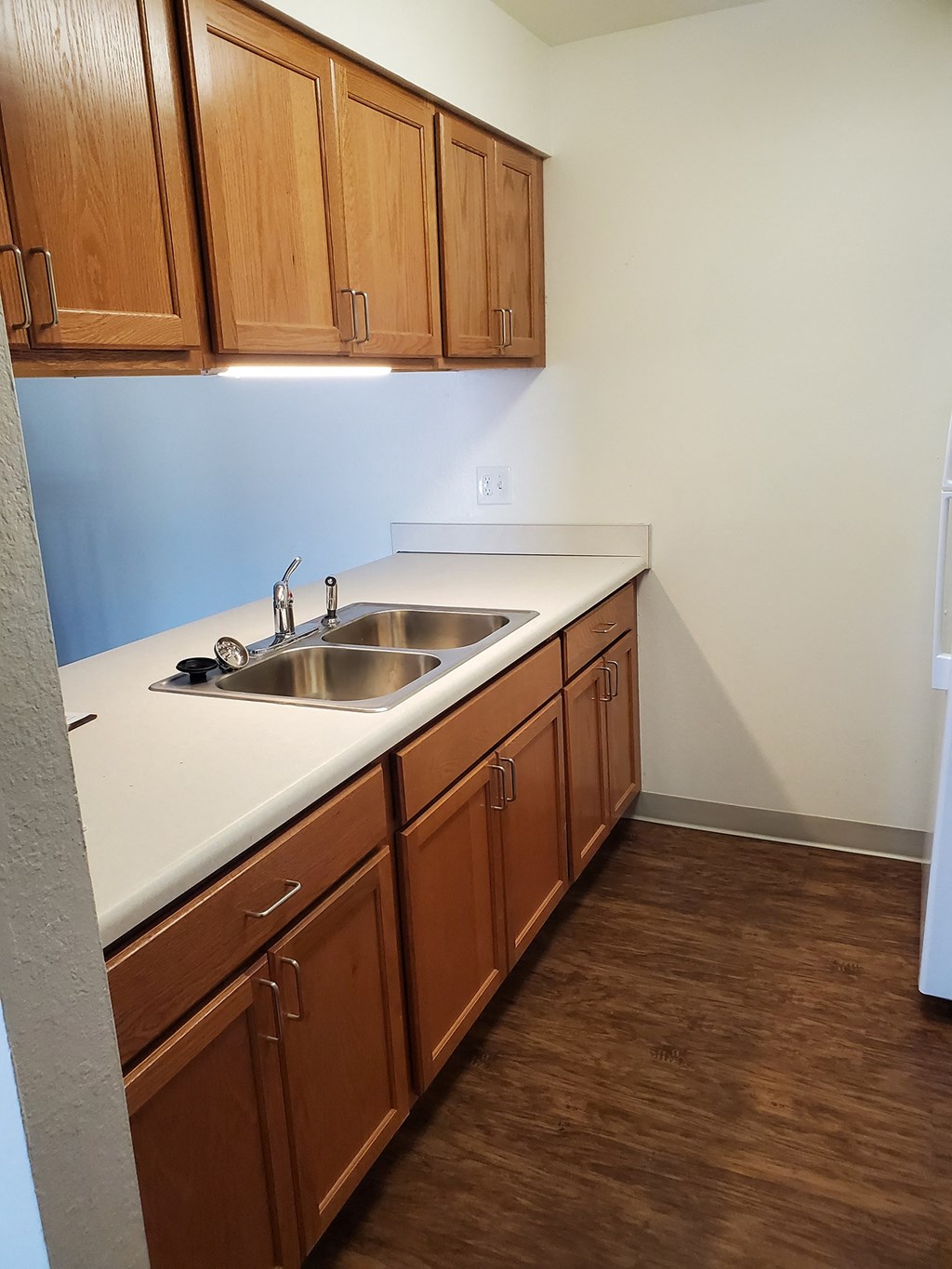 an empty kitchen with a sink and wooden cabinets