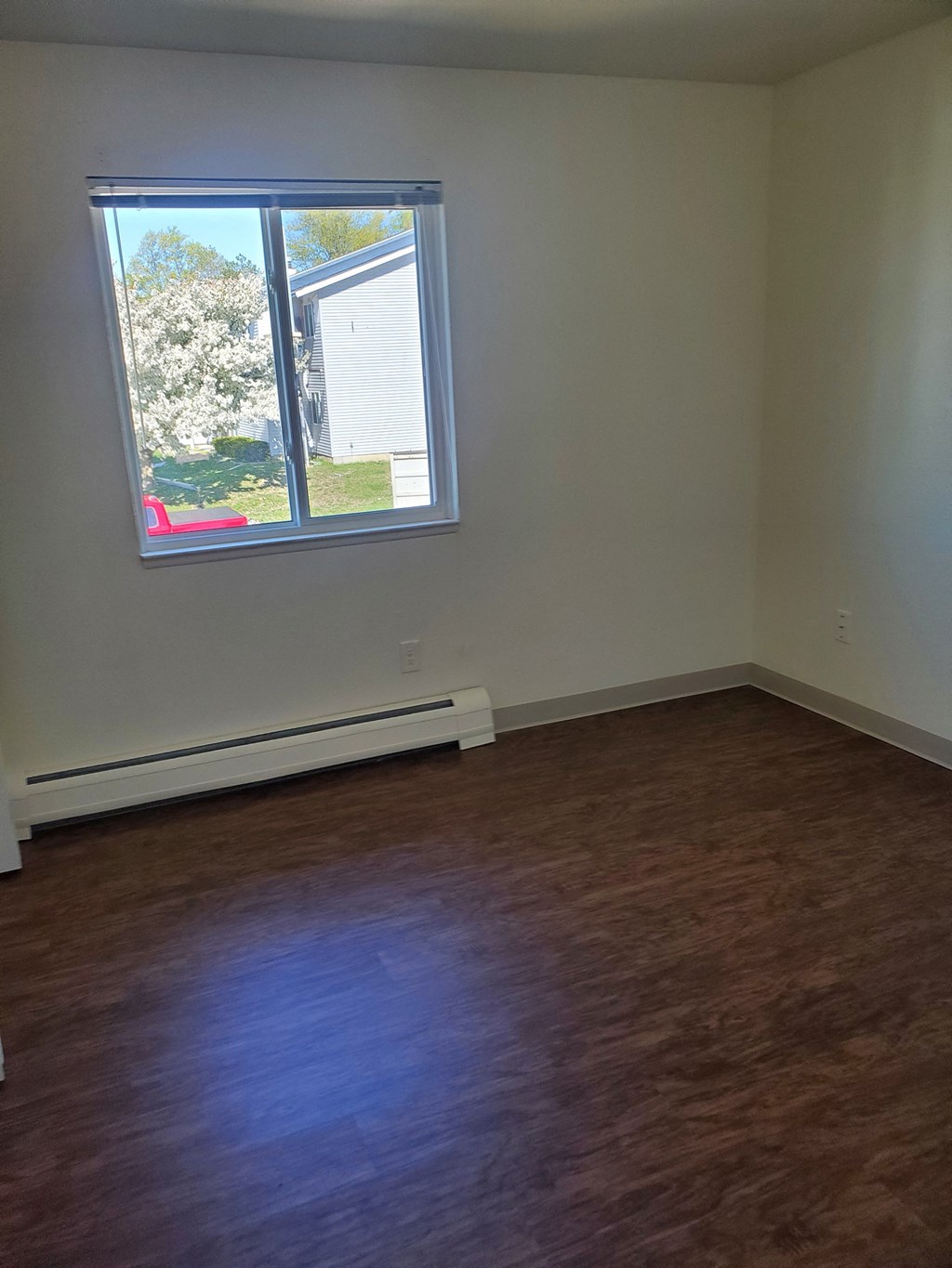 an empty room with a window and wooden floors
