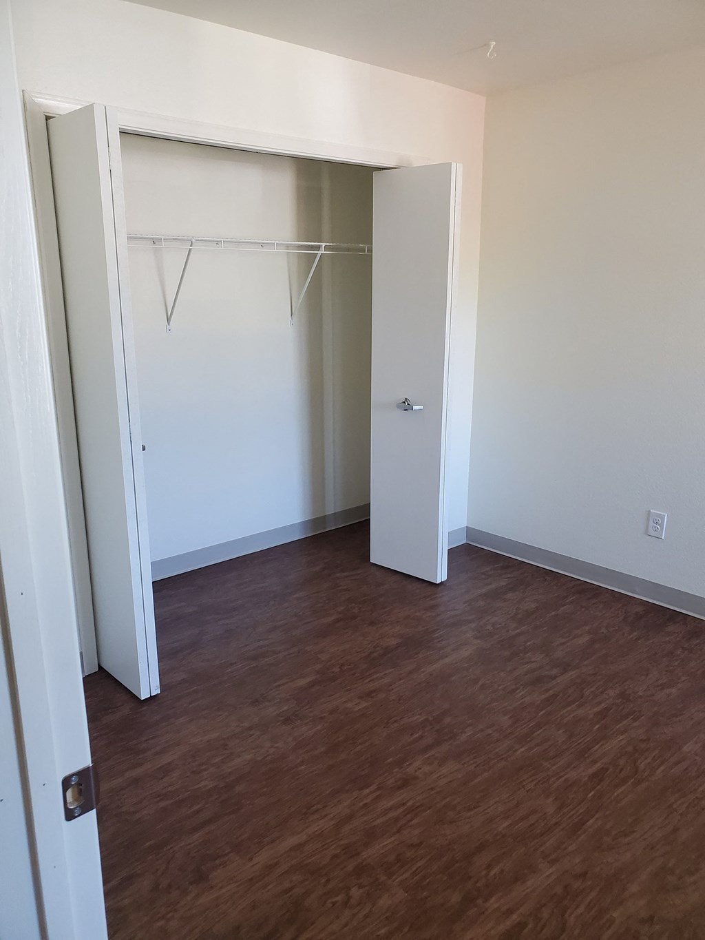 an empty bedroom with a closet and a wooden floor
