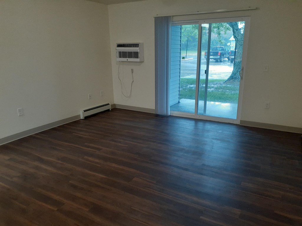 an empty living room with wooden floors and a sliding glass door