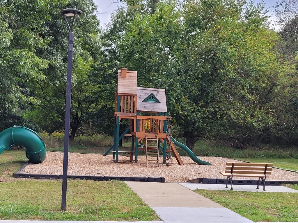 a playground with a wooden playset and a bench