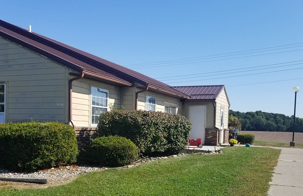 the front of a house with a driveway and hedges