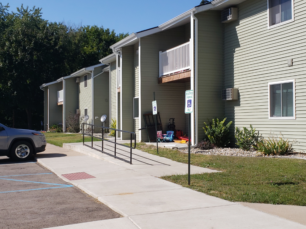 an apartment building with a sidewalk and a car parked outside