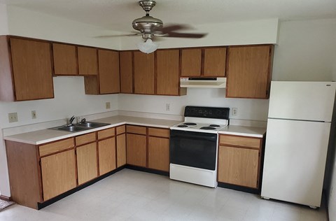 an empty kitchen with wooden cabinets and black and white appliances