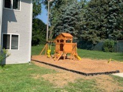 a backyard playground with a swing set and a house