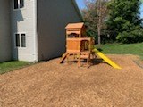 a yellow swing set in a backyard next to a house