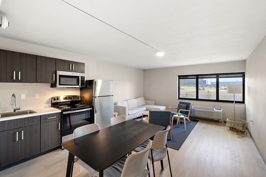 a kitchen and living room with a black dining table and white couches at The Block at Sterling Heights, Sterling Heights, Michigan
