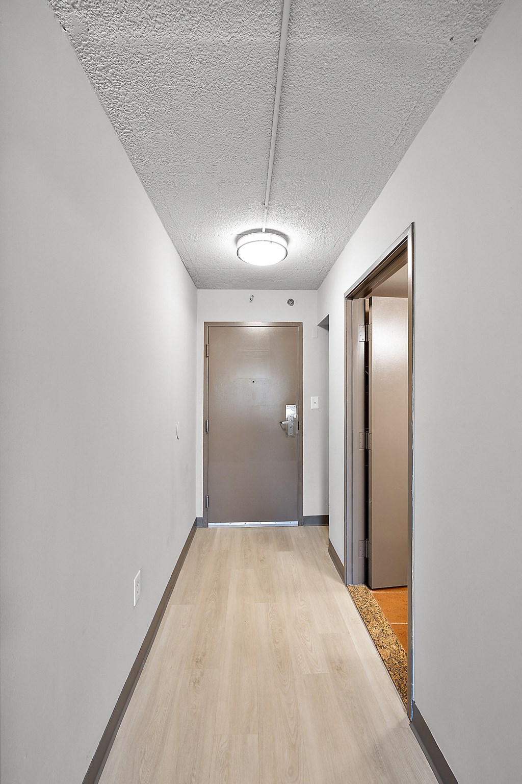 an empty hallway with a door to a closet and a door way to a room