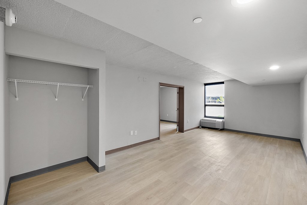 the living room and dining room of an apartment with wood floors and white walls