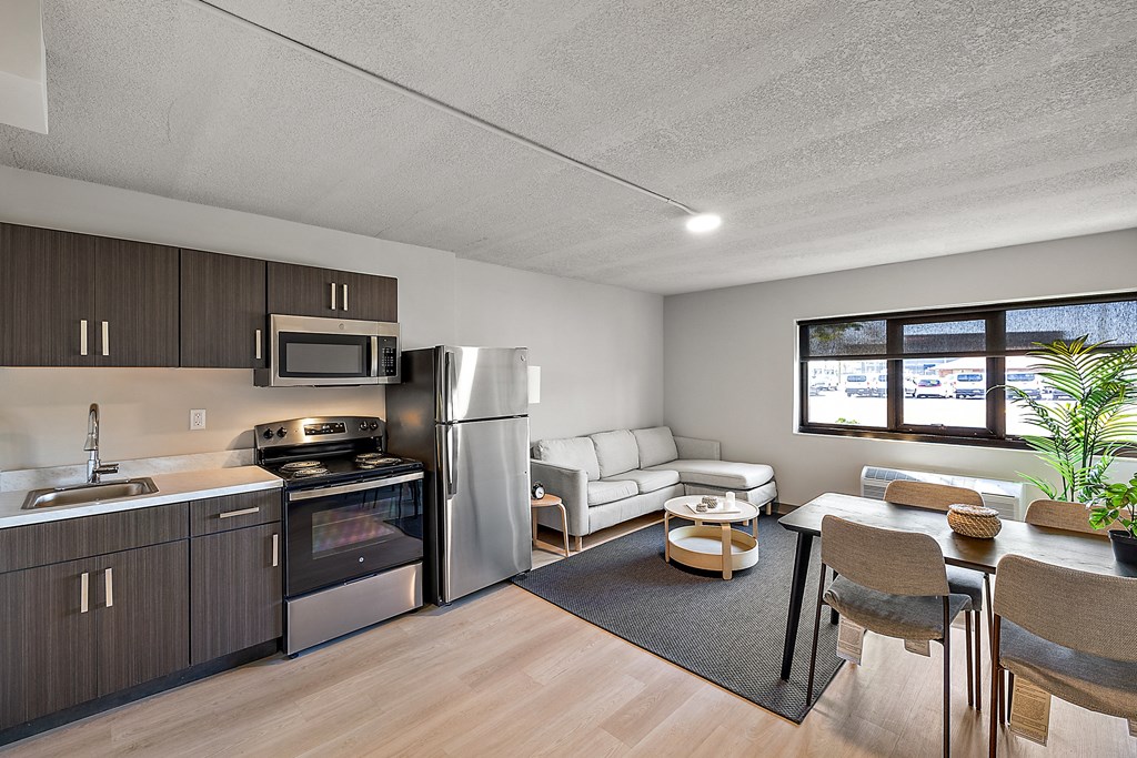 a kitchen and living room with stainless steel appliances and a table and chairs