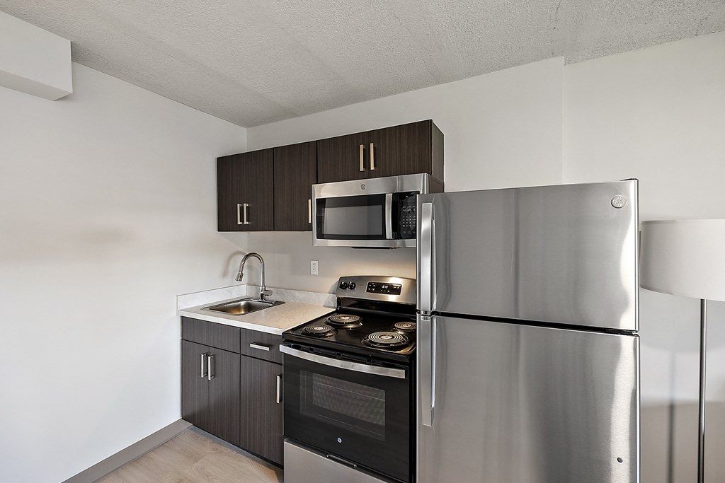 an empty kitchen with stainless steel appliances and a refrigerator