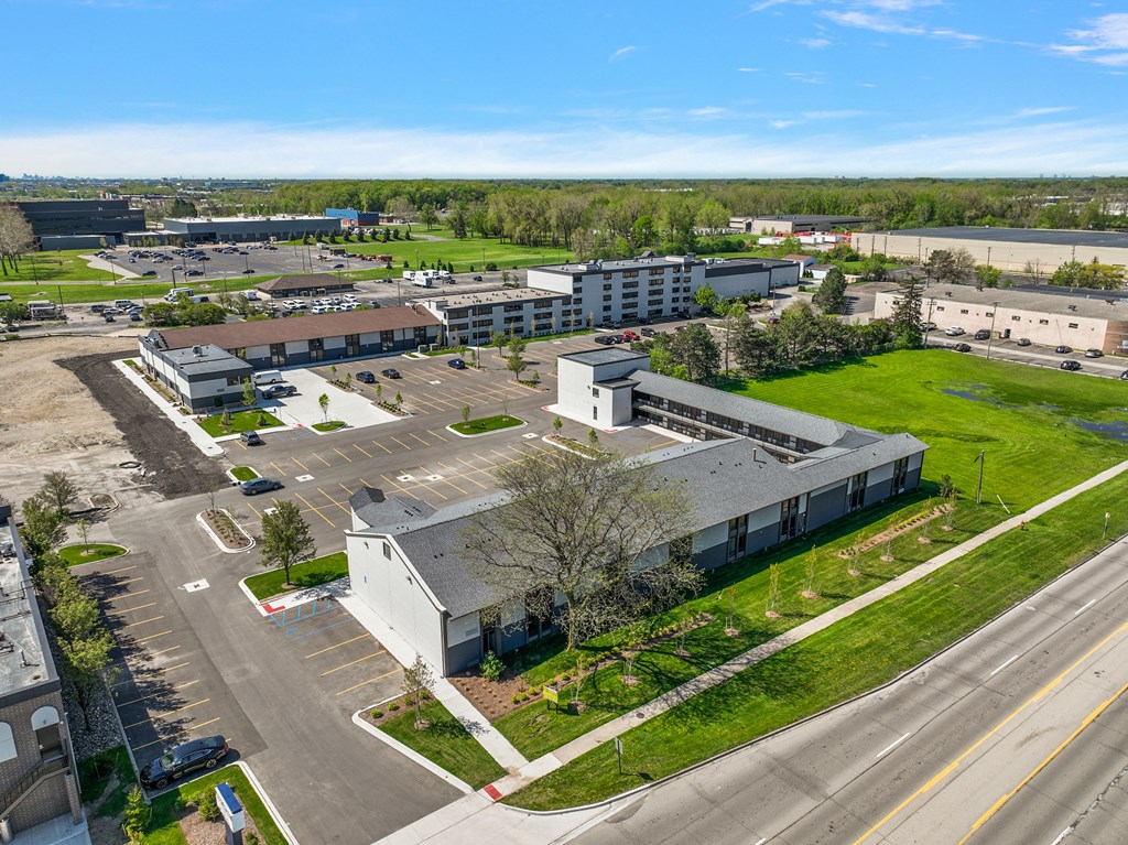 an aerial view of a building with a green lawn and a parking lot