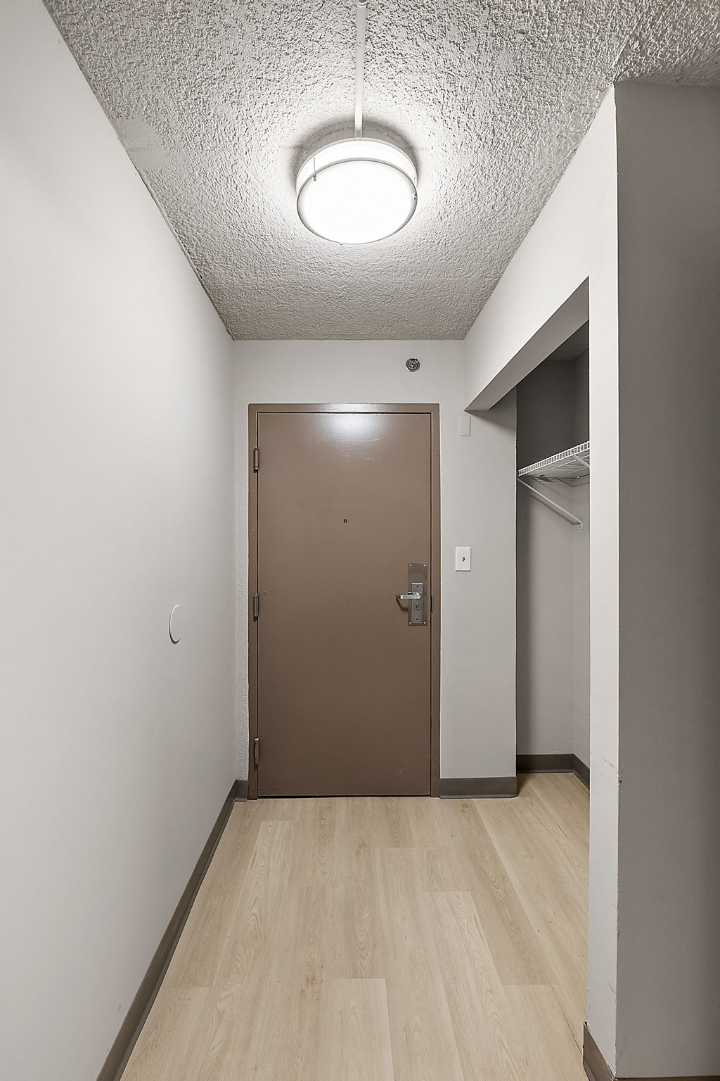 an empty corridor with a door to a closet and a wardrobe