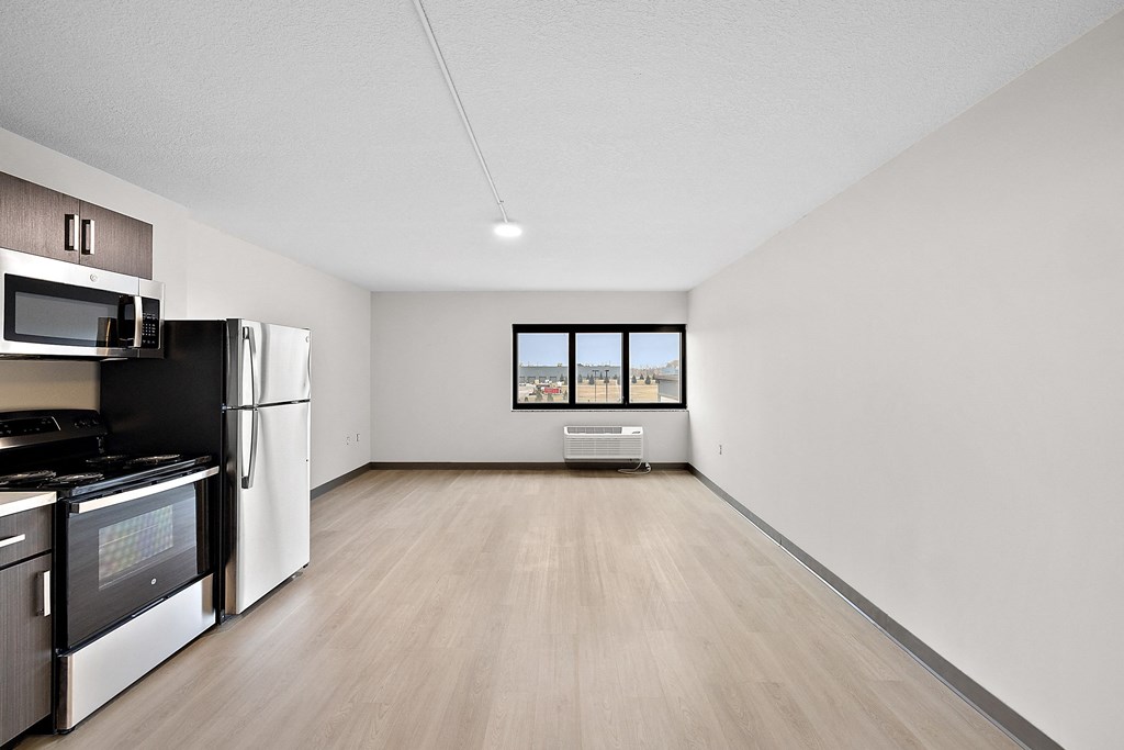a kitchen and living room with white walls and wood floors at The Block at Sterling Heights, Sterling Heights, 48312