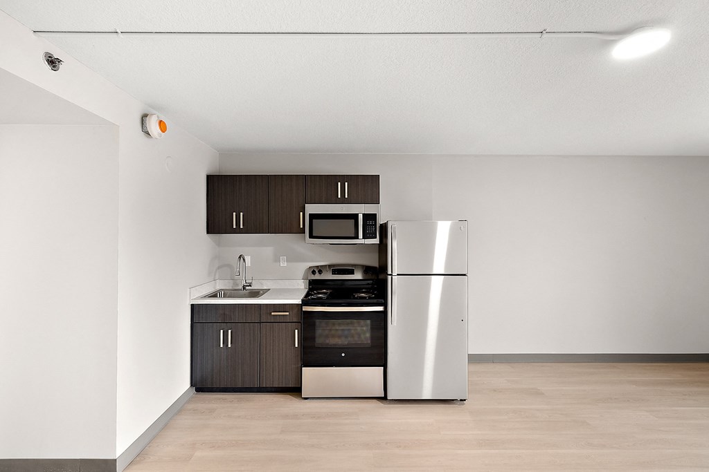 a kitchen with a white refrigerator freezer next to a stove top oven at The Block at Sterling Heights, Sterling Heights, MI, 48312