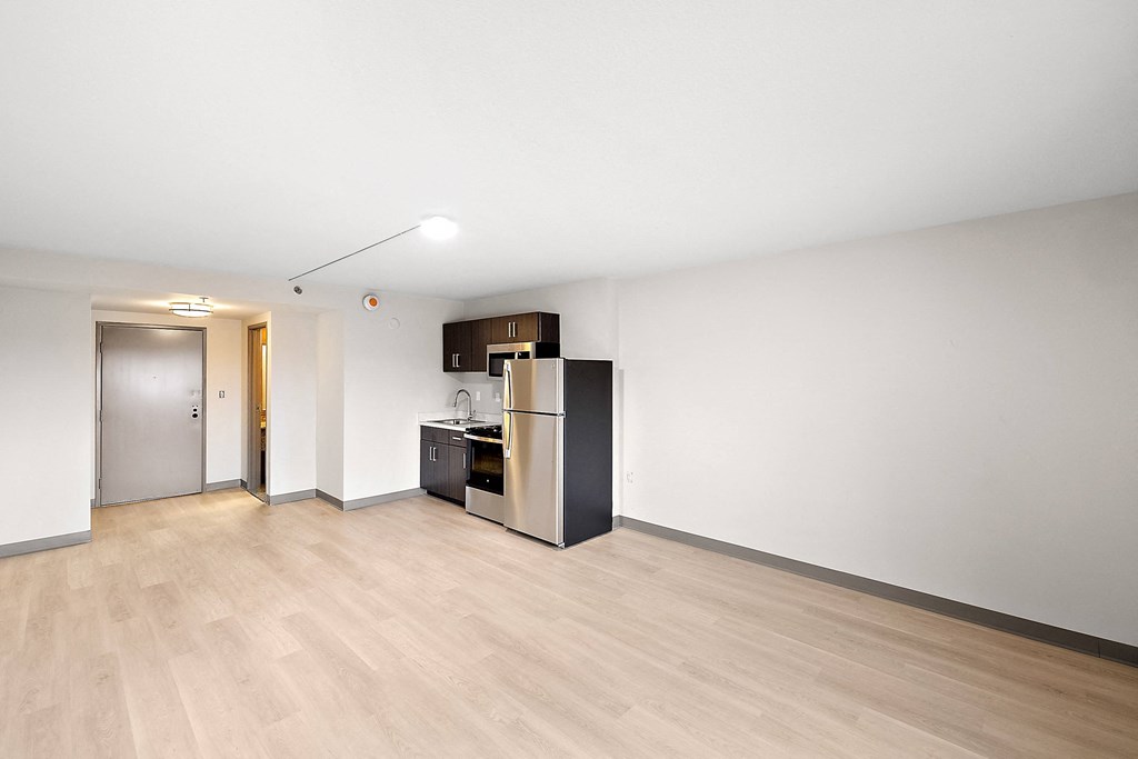 a bedroom with a medium sized bed and a refrigerator in a room at The Block at Sterling Heights, Sterling Heights