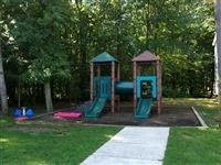 a playground with two swings and a sidewalk