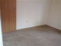 an empty room with a wooden door and a gray carpet