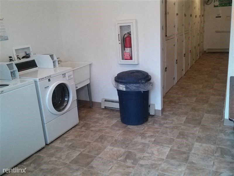 a laundry room with a washing machine and a trash can