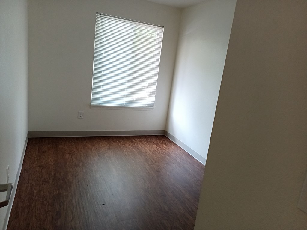 an empty room with wooden floors and a window