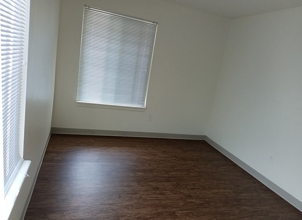 an empty room with wood floors and a window